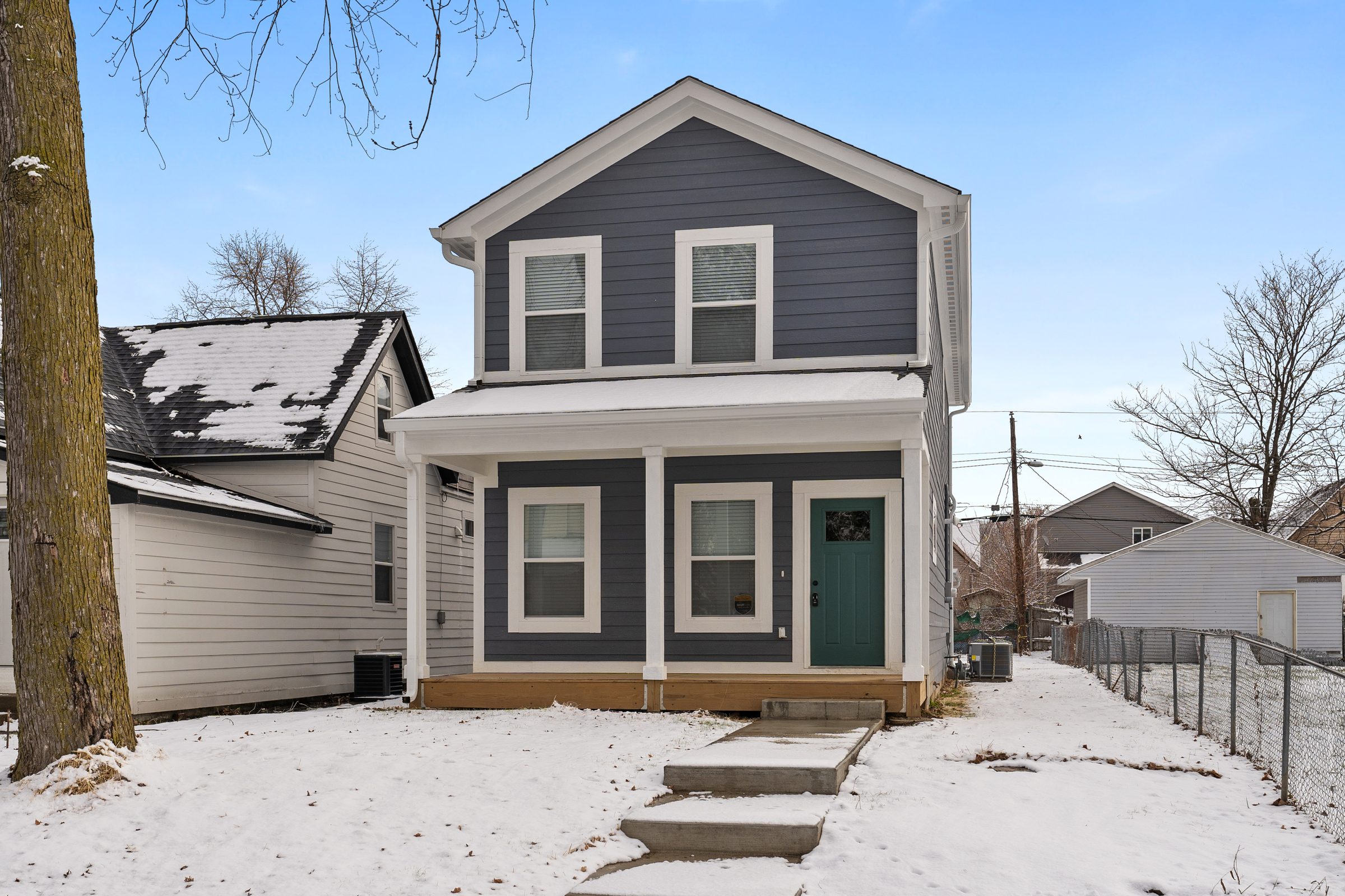 Slate-blue home with a teal door in fresh snow